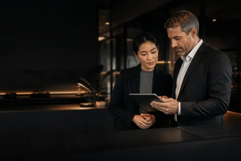 Two business partners reviewing a tablet together in a modern financial workspace