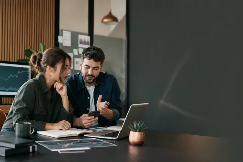 Content creators planning a trading education campaign with a laptop and phone
