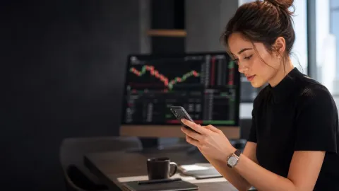 Young professional using a mobile trading application in a modern workspace